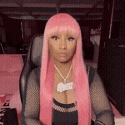 Nicki Minaj In Pink Wig And Necklace Sitting In Chair GIF