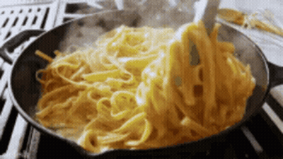 Noodles Are Being Stirred In A Pan With A Spoon GIF