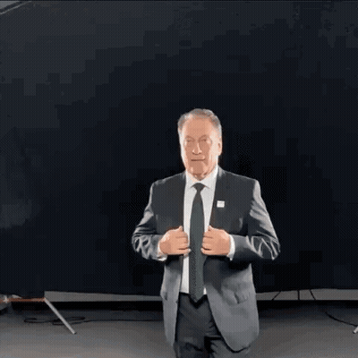Older Man In Suit And Tie Against Black Background GIF