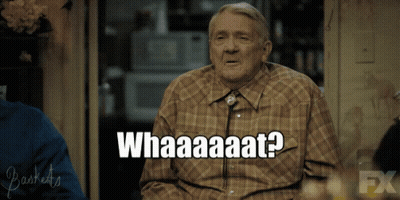 Older Man Sitting In Front Of Whataaaat Sign GIF