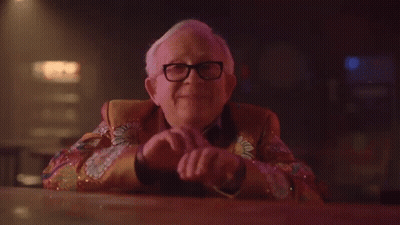 Older Man Smiling In Colorful Jacket At Bar GIF
