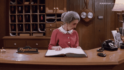 Older Woman At Reception Desk With Registration Sign GIF
