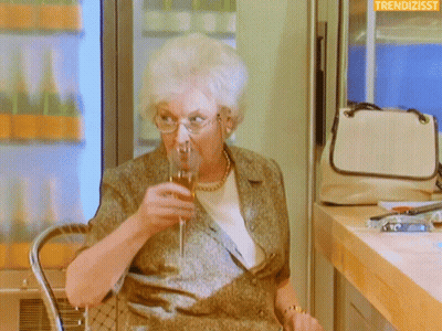 Older Woman Drinking Wine With Trendizsst Logo GIF