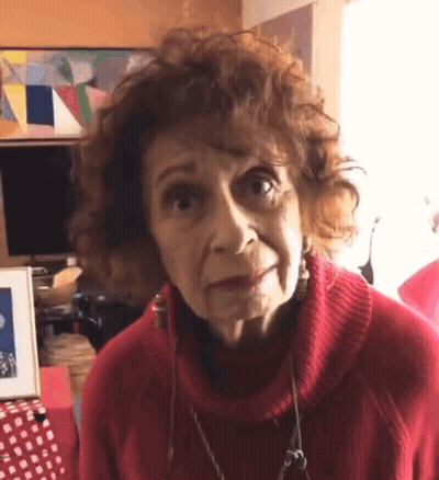 Older Woman In Red Sweater And Earrings Looking GIF