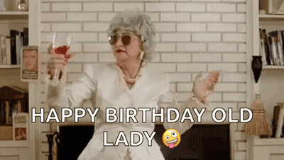 Older Woman Sitting By Fireplace Holding Wine Saying Happy Birthday Old Lady GIF