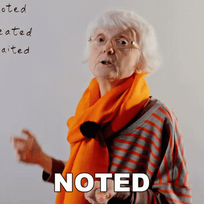 Older Woman With Glasses and Orange Scarf by Noted Board
