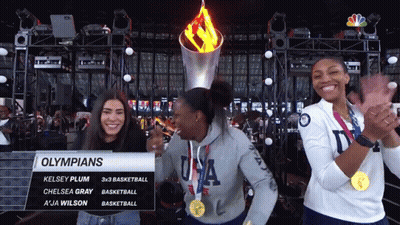 Olympians Kelsey Plum Chelsea Gray And A Ja Wilson Are Standing In Front Of The Torch GIF
