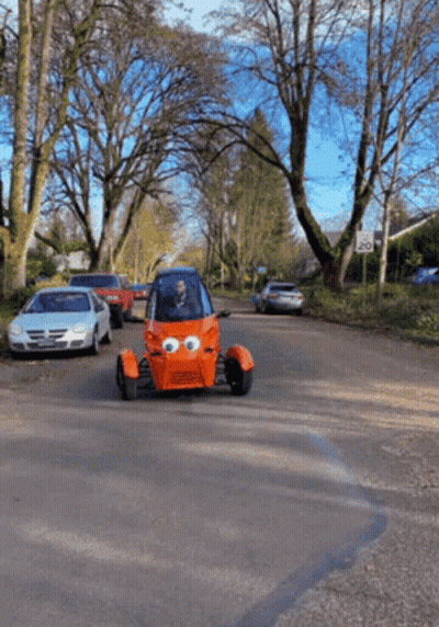 Orange Car With Big Eyes Driving Down Street GIF