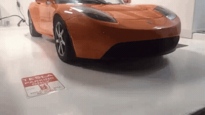 Orange Tesla Parked By Tesla Parking Sign GIF