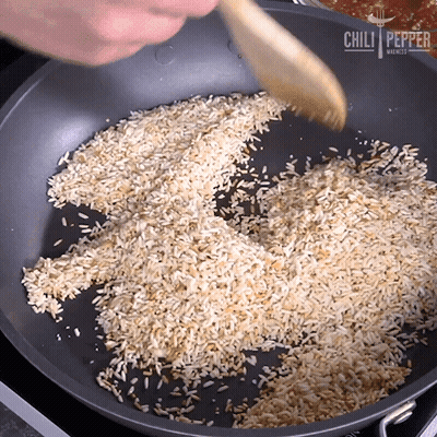 Pan Of Rice Stirred With Wooden Spoon From Chili Pepper Markets GIF