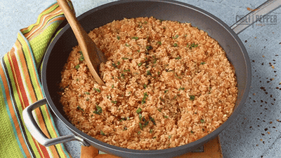 Pan Of Rice With Wooden Spoon And Chili Peppers GIF