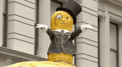 Peanut Mascot In Top Hat And Suit In Front Of Building GIF