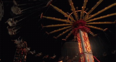 People Are Riding A Merry Go Round At A Carnival At Night .. GIF
