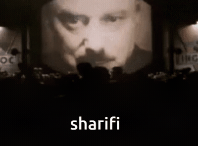 People Before Screen With Man's Face And Sharifi GIF