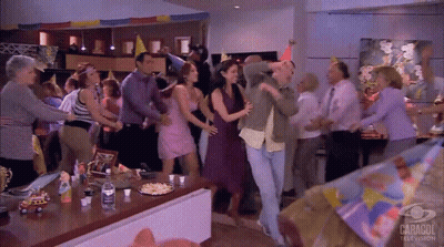 People Dancing In Room With Caragol TV Sign GIF