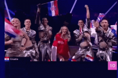 People Dancing On Stage Holding Flags GIF