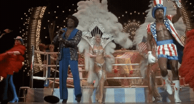People Dancing On Stage, One With American Flag Hat GIF