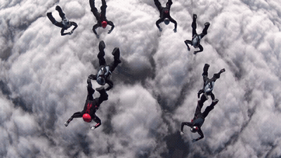 People Flying, One In Red Helmet GIF