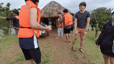 People In Life Jackets Standing In Field GIF