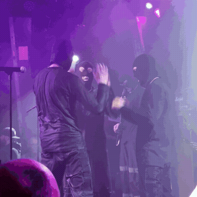 People In Ski Masks On Stage With Purple Lights GIF