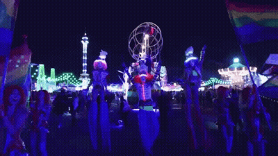 People on Stilts in Front of Carnival Ride