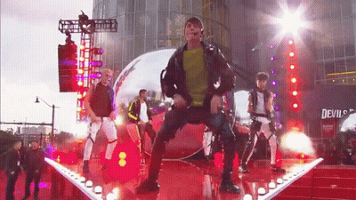 People Performing On Stage In Front Of Building Saying Devil's GIF