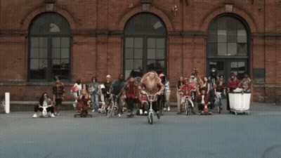 People Riding Bicycles In Front Of Wu Building GIF