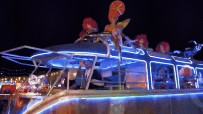 People Riding Lit Up Boat At Night GIF
