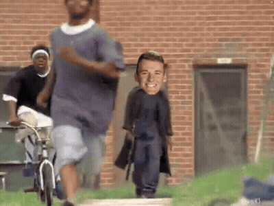 People Running In Front Of Brick Building With Man On Back GIF