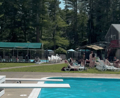 People Sitting Around Pool With Chairs And Umbrellas GIF