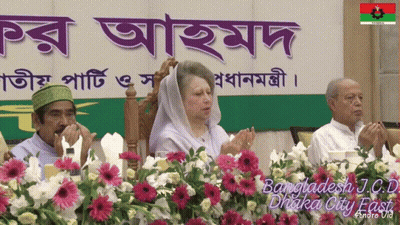 People Sitting In Front Of Bangladesh J.C.U Sign GIF