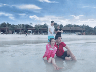 People Sitting On Beach With Woman Taking Photo GIF