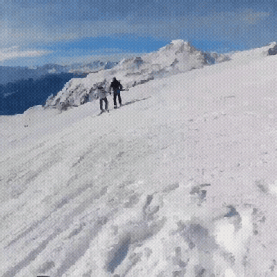 People Skiing Down Snowy Mountain GIF
