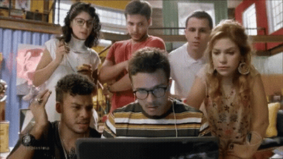 People Standing Around Man Looking At Laptop GIF