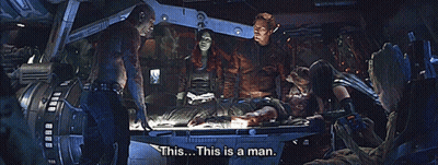 People Standing Around Man On Table Saying This Is A Man GIF
