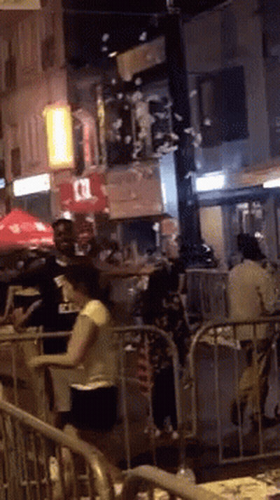 People Standing By Fence On Crowded Street GIF