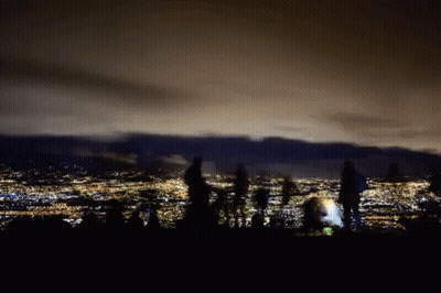 People Standing On Hill Over City At Night GIF