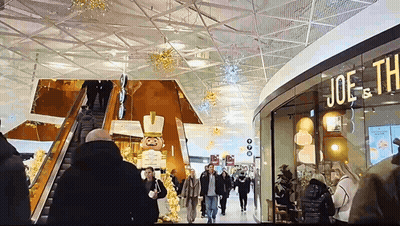 people walking in a shopping mall with a sign that says joe th
