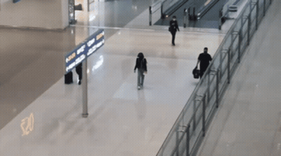 People Walking In An Airport With A Sign That Says ' Arrivals ' GIF
