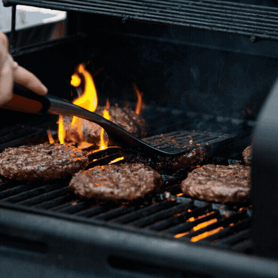 Person Cooking Hamburgers On Grill With Flames GIF
