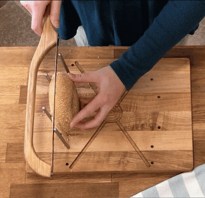 Person Cutting Bread On Wooden Board GIF