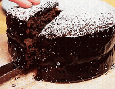 Person Cutting Chocolate Cake With Powdered Sugar GIF