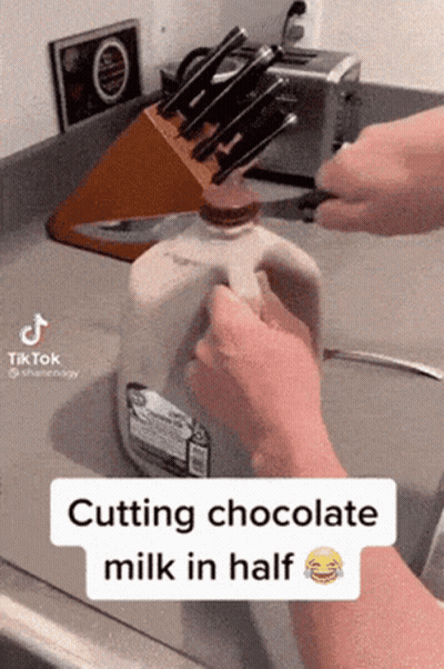 Person Cutting Chocolate Milk In Half With Knife GIF