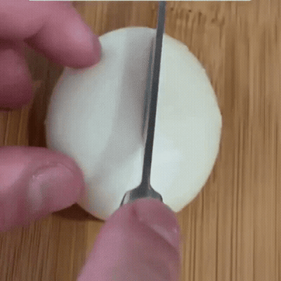 Person Cutting Egg On Cutting Board With Knife GIF