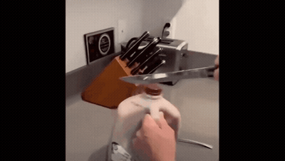 Person Cutting Gallon Of Milk With Knife GIF