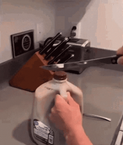 Person Cutting Gallon Of Milk With Knife GIF