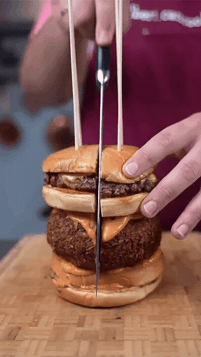 Person Cutting Hamburger In Half With Knife GIF