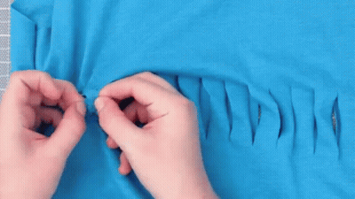Person Cutting Hole In Blue T-Shirt With Scissors GIF