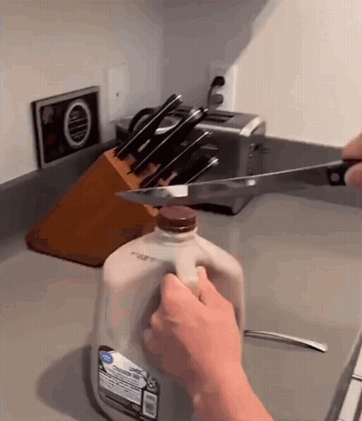 Person Cutting Into Gallon Of Milk GIF