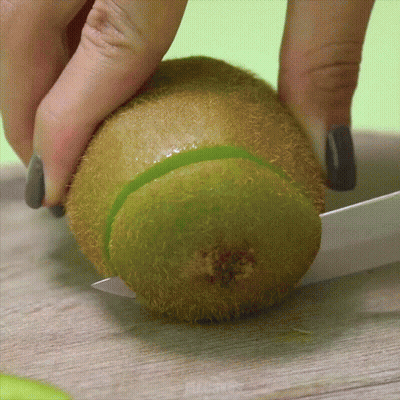 Person Cutting Kiwi In Half With Knife GIF